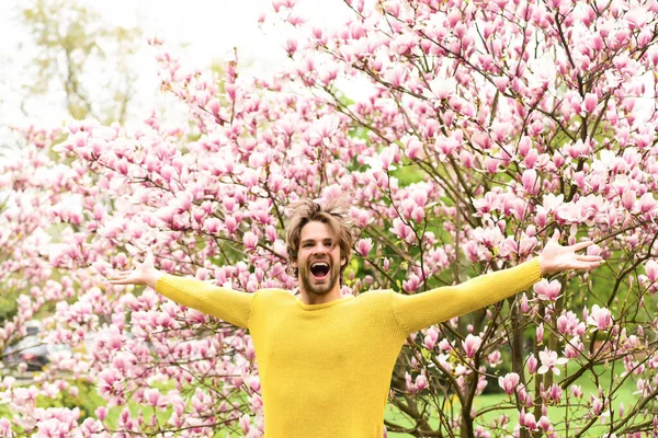 Facet w żółtym swetrze z otwartymi dłońmi na kwiatowym tle — Zdjęcie stockowe