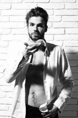 Beyaz tuğla duvarda yakışıklı, sakallı, maço seksi bir adam.