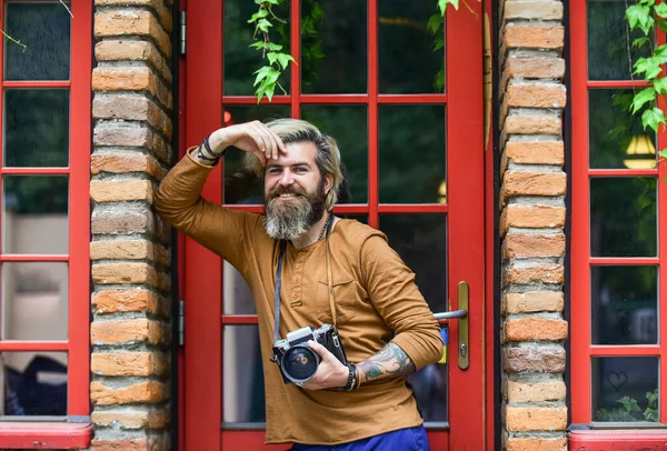 Brutal man med retrokamera. Kreativ karriär. Professionell fotograf använder vintage kamera. Fotografering. Kreativ fotograf urban bakgrund irländsk arkitektur stil. Fotografering. — Stockfoto