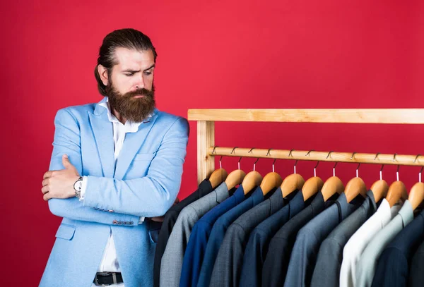 Handsome man in smart casual wear looking at suits and choosing. stylish mens clothing on hanger stand in room. business fashion style. dry cleaning service. style and people concept — Stock Photo, Image