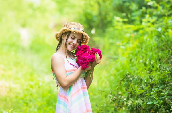 Vigyázok a természetre. Boldog gyermek szalmakalapban. A természet hajviselete. Anyák napja. Boldog nőnapot! Egy virágos kisgyerek portréja. Szerelem és szépség. lenyűgöző lány csokor rózsa virágok — Stock Fotó