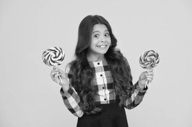 Zararlı yiyecekler. Tatlılara bayılırım. Şeker bağımlılığı. Tatlı şekerli mutlu çocuk. Elinde lolipop tutan çocuk şeker sarısı arka planda. Şekerli mutlu çocuk. Okul beslenmesi. Kalori ve enerji