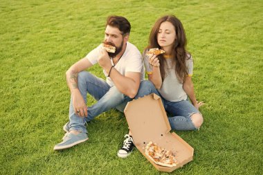 Yaz pikniği kolay ve hızlı fikirler. Fast food. Sakallı adam ve kadın peynirli pizzanın tadını çıkarın. Birbirlerine aşık çiftler dışarıda pizza yiyorlar. Aç öğrenciler yemek paylaşıyor. Pizza yiyen bir çift çimlerde dinleniyor.