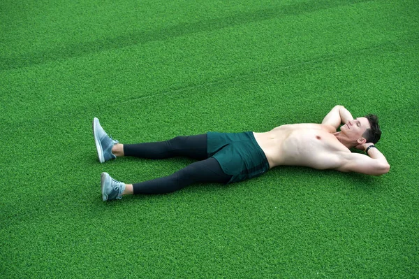 Подходящий молодой человек отдыхает после тренировки. расслабиться после занятий йогой. Разум и тело в гармонии. Здоровый и здоровый. Парень без рубашки лежит на зеленой траве. время для отдыха. нуждаются в некоторой расслабленности — стоковое фото