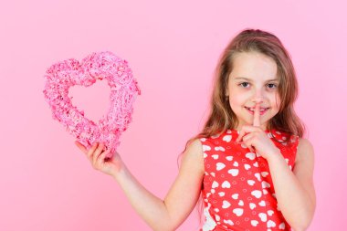 Gizli ve sessiz kız pembe arka planda pembe kalbi tutuyor..