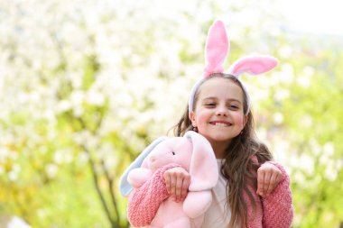Bahçede çiçek açan ağaçlarla tavşan gibi poz veren mutlu kız.