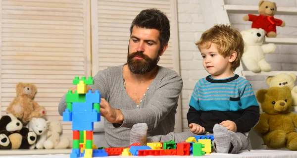 Arka planda oyuncakları olan baba ve çocuk blokları inşa ediyor. — Stok fotoğraf