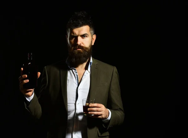 Man holding glass of whiskey or bourbon and bottle