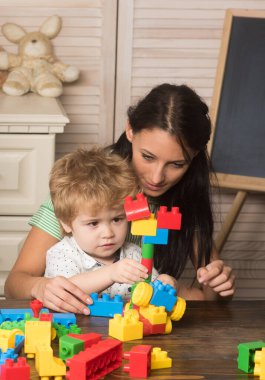 Anne ve oğlu açık tahta arka planda oyun odasında..