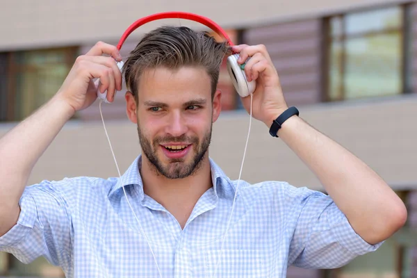 Young man listening music with headphones on urban background, defocused.