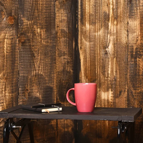 Filiżanka herbaty lub kawy i pamiętnik na brązowym drewnianym tle. — Zdjęcie stockowe