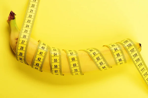 Banán se žlutou páskou pro měření postavy. — Stock fotografie