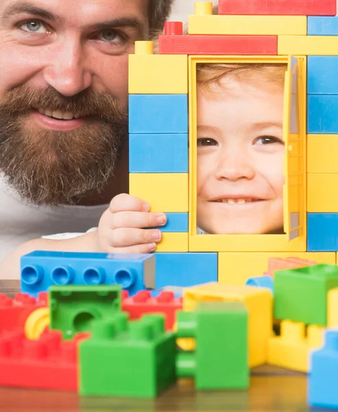 Padre e hijo con caras sonrientes mirando a través de la construcción de juguetes. — Foto de Stock