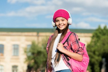 Modern çocukların şarkısı. Mutlu kız açık havada kulaklık takıyor. Küçük çocuk müzik dinler. Hi-Fi ses sistemi. Dijital ses. Modern teknoloji. Eğlence ve eğlence. Modern yaşam tarzı