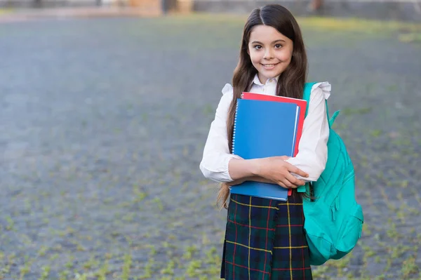 Liten flicka formell stil uniform och ryggsäck hålla böcker, skola schema koncept — Stockfoto