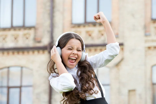 Una pupila sonriente. Un verdadero éxito. Feliz canción. Ocio y descanso. Hermoso peinado. Niño feliz al aire libre. Una colegiala alegre. Colegiala relajándose. Concepto de infancia feliz. Día internacional de los niños — Foto de Stock