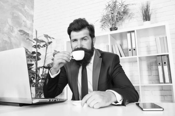 A primera hora de la mañana. El barbudo bebe café matutino en la oficina. El gerente disfruta de una bebida caliente por la mañana. Té de desayuno. Última rutina matutina — Foto de Stock
