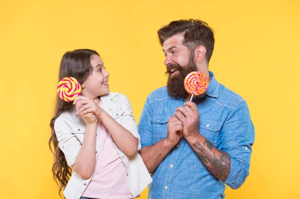 Gelukkig familie vader en dochter eten lolly gele achtergrond, suiker dieet concept — Stockfoto