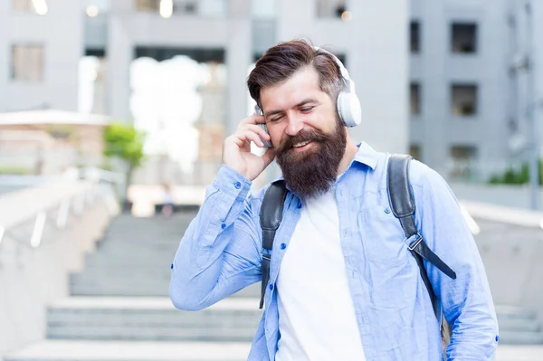 Good sound. Daily route to work. Walking through empty streets. Alone with music. Modern life. Man with headphones walking city center. Listening music. Handsome hipster with backpack walking street