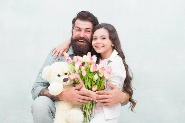 Der beste Tag aller Zeiten. Glückliche Familie feiert Urlaub. Kleines Kind und Vater halten Blumen und Spielzeug in der Hand. Feiertagsfeier. Geburtstag feiern. Souvenirladen. Spielzeugladen. Blumenladen. Frühjahrsferien — Stockfoto