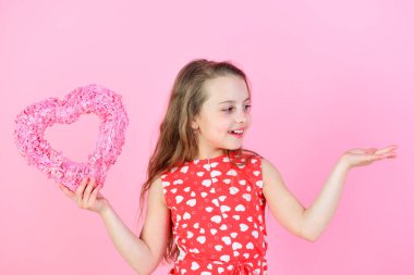 Pembe arka planda kalbi olan mutlu bir kız.