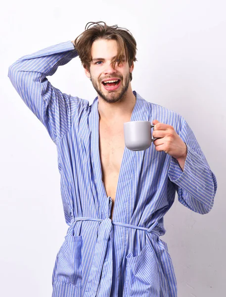 Guy in home or bath clothes drinks tea or coffee.