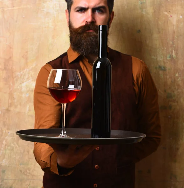 Waiter carrying tray with beverage. Glass and dark wine bottle — Stock Photo, Image