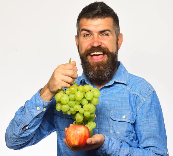 Man med skägg rymmer massor av gröna druvor och äpple — Stockfoto