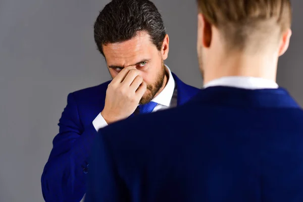 Man in suit listening his partner with tired expression.