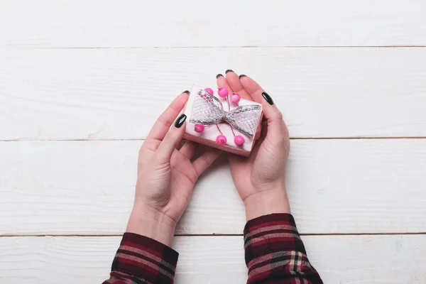 Femme mains tenir boîte enveloppée dans du papier rose avec arc — Photo