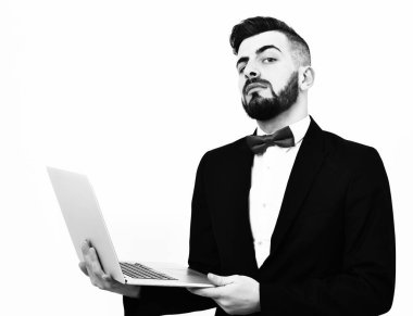 Sakallı meraklı ve gururlu broker beyaz dizüstü bilgisayar tutuyor.