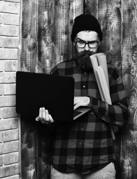 Barbudo brutal caucasiano hipster segurando laptop e papel artesanal — Fotografia de Stock