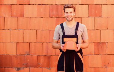 Onarımları yapın. İşçi tuğlası arka plan. Bina ve inşaat. Profesyonel tamirci şapkası. İş kıyafetleri içinde bir erkek müteahhit. Adam ev inşa ediyor. Usta mimar tamir ve onarım