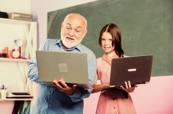 回学校去在线课程。数字科学教师。老师帮助学校的女孩。带着男老师学习的小女孩拿着笔记本电脑。教孩子的互联网课程。现代学校。现代教育家 — 图库照片