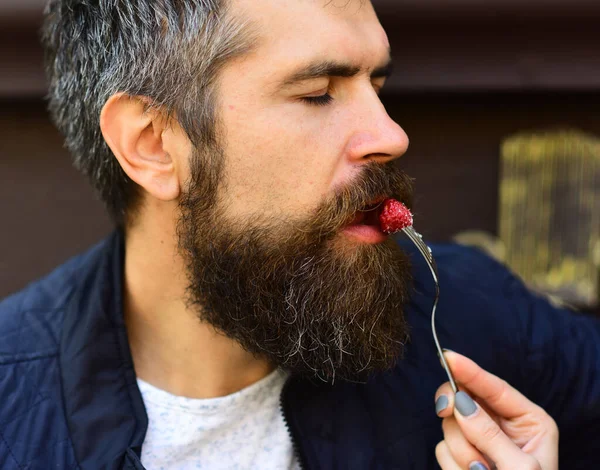 ひげを生やした男性は背景がぼやけてラズベリーを食べる. — ストック写真