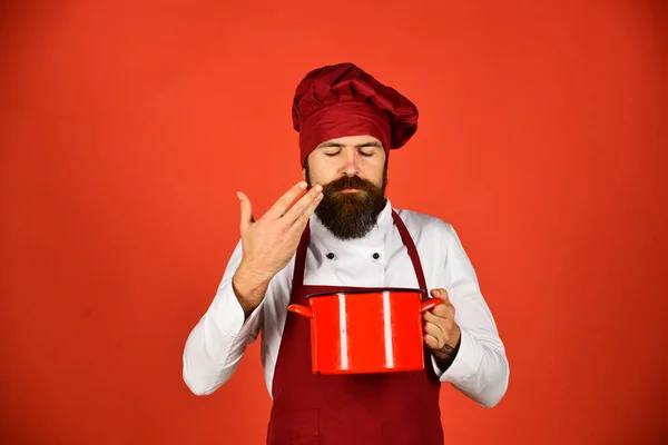 Koken met dromerig gezicht in bordeaux uniform ruikt soep — Stockfoto