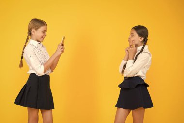 Küçük mankenler. Eğitim blogu. Yeni teknoloji. Online eğitim. Bilgi günü. Akıllı telefonlu mutlu öğrenciler. Çocuklar fotoğraf çeker, arkadaşlık eder. Okul üniformalı küçük kızlar. Okula geri dön.