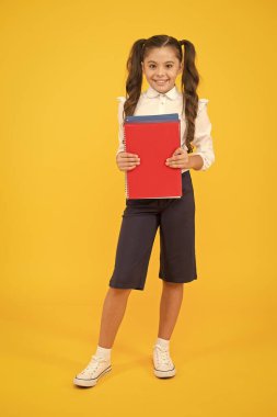 Bilgi ışıktır. Sarı arka plan üzerine kitap tutan sevimli küçük bir kız. Okul bilgisi elinde olan sevimli küçük bir çocuk. Bilgi günü veya 1 Eylül. Bilgi ve beceri kazanıyorum