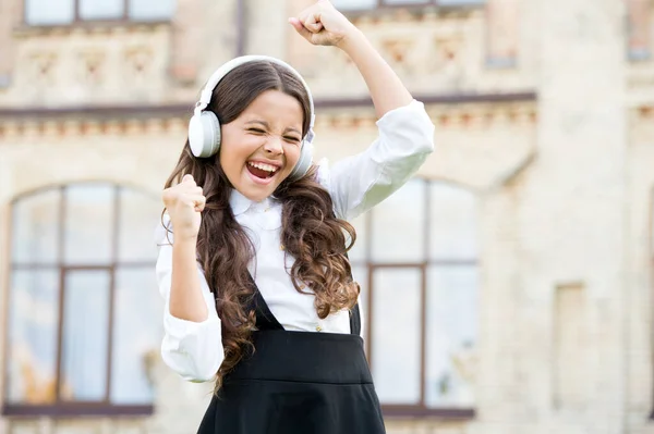 Mi día perfecto. felicidad infantil. niño en auriculares digitales. pequeña estudiante escuchar música al aire libre. de vuelta a la escuela. niña pequeña que parece inteligente e inteligente. colegiala feliz en uniforme elegante — Foto de Stock