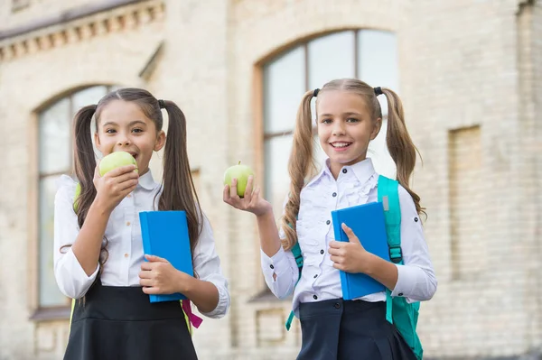 Estudantes meninas colegas de classe com mochilas almoçando na escola, comendo conceito de maçã — Fotografia de Stock