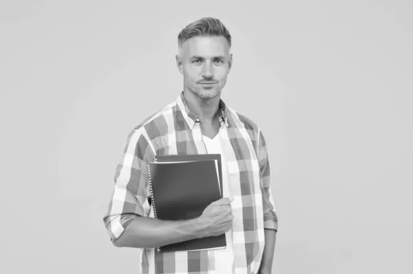 Homme avec dossier fond jaune. Un homme d'affaires tient un livre pour des notes. Il a un bloc-notes pour écrire. beau professeur d'école ou d'université. adulte homme étudiant tenant des cahiers. Inspiré à travailler dur — Photo