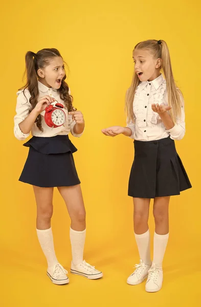 O alarme está a tocar. Hora do almoço. Horário escolar. Alunas e despertador. Crianças alunos da escola adorável roupa uniforme formal. As crianças seguram o tempo de contagem do despertador. Tempo para descansar e descansar — Fotografia de Stock