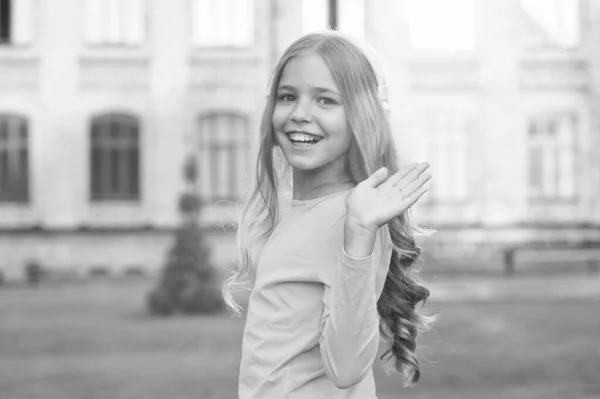 Hallo, schoonheid. Gelukkig kind zwaai hand buiten. Klein kind glimlach in casual stijl. Klein kind draagt lang golvend haar. Schoonheidssalon. Mode en stijl. Kinderopvang en kindertijd — Stockfoto