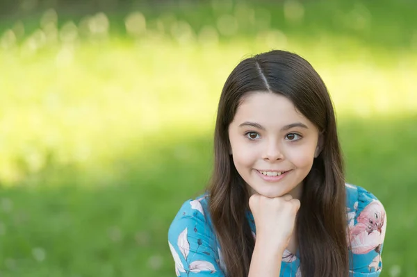 Liten flicka med långt hår avkopplande i parken solig dag grönt gräs bakgrund, optimism och positivitet koncept — Stockfoto