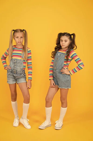 Moderno y elegante. Tienda de moda. Debe tener cómplice. Colores vibrantes. Moda moderna. Moda infantil. Pelo largo de chicas. Lindos niños mismos trajes. Niñas usando ropa de arco iris. Trajes a juego —  Fotos de Stock