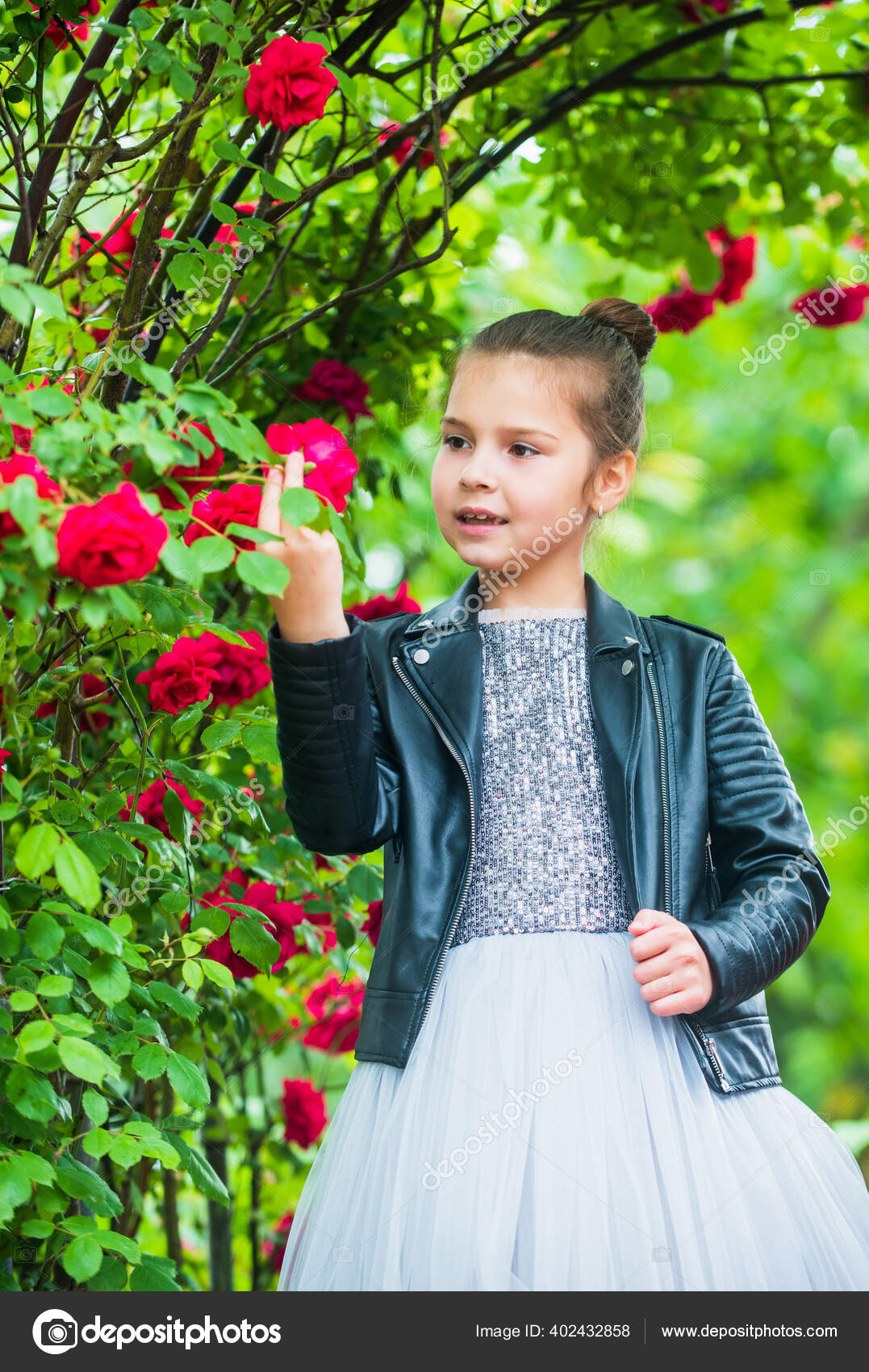 Trendy girl fancy dress and leather jacket in roses garden cool