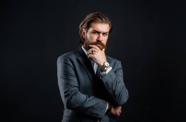Mükemmel kıyafet. Modern görünümlü şık, olgun bir adam. Erkek ofisindeki gardırop. Modaya uygun bir adam el saati takar. Resmi manken. Gri arka planda yakışıklı bir adam. Ciddi sakallı iş adamı