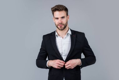 Karizmatik iş sahibi. Şık bir emlakçı. Yakışıklı adam resmi takım elbise giyer. Gömlek ve ceket giyen kendine güvenen bir iş adamı. patron erkek. Gri arka planda seksi CEO. Modern ofis hayatı. Genç uzmanlık
