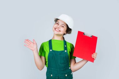 Planın önünde gülümseyen miğferli bir mimar. Gelecekteki iç mimar. Kask takan çocuk klasörde. Plan dosyası olan bir çocuk işçi. İnşaat alanında klasörlü küçük bir kız. Boşluğu kopyala
