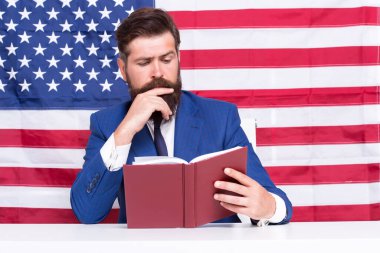 Hipster, Amerikan bayrağı arkaplanı okuyor, sıkı çalışıyor.